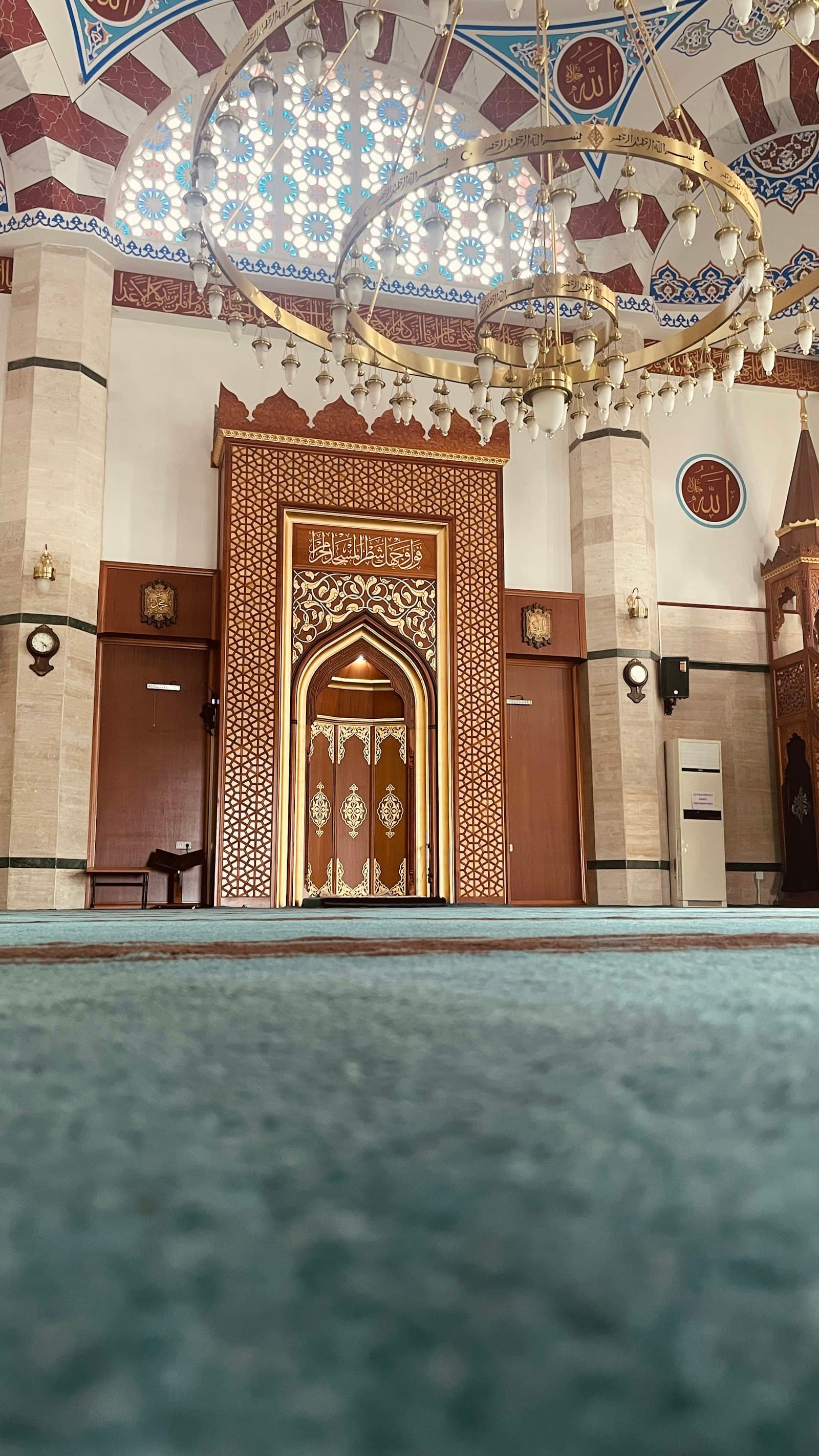 Ahşap oymalı mihrap ve önünde turkuaz cami halısı